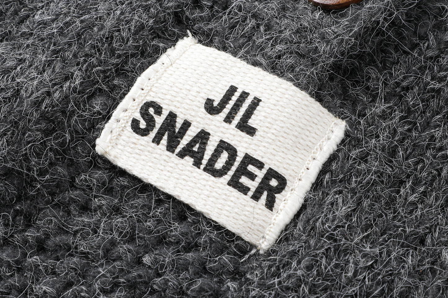 フーディーニットカーディガンの上質なニット生地のテクスチャとボタンの拡大画像。