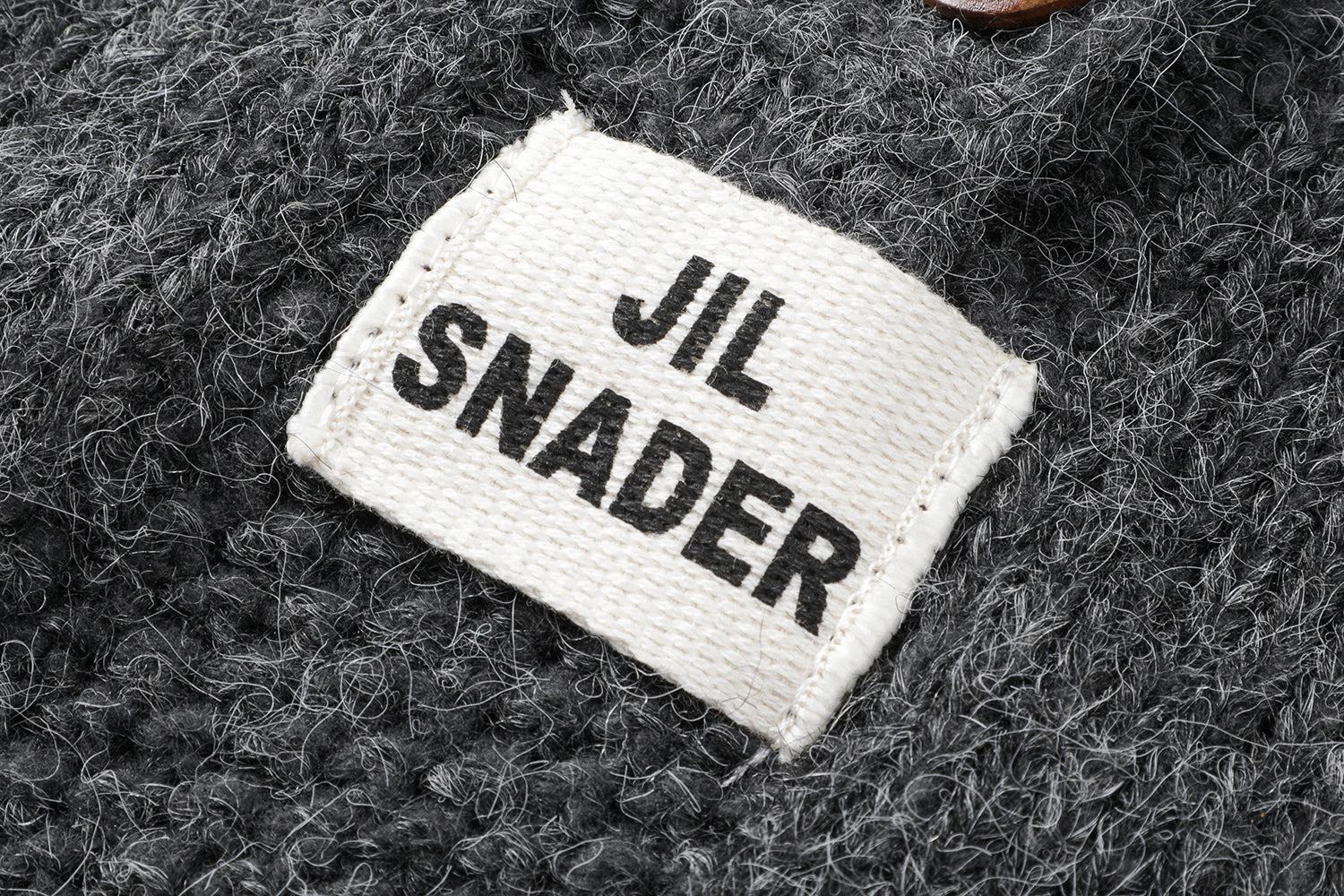 フーディーニットカーディガンの上質なニット生地のテクスチャとボタンの拡大画像。