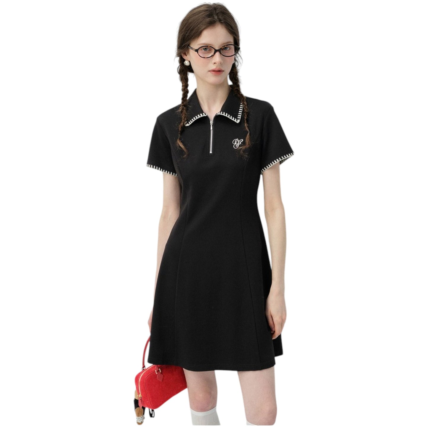 バイカラーのポロ襟とフロントジップが特徴の、黒いミニワンピースを着用した女性モデル。