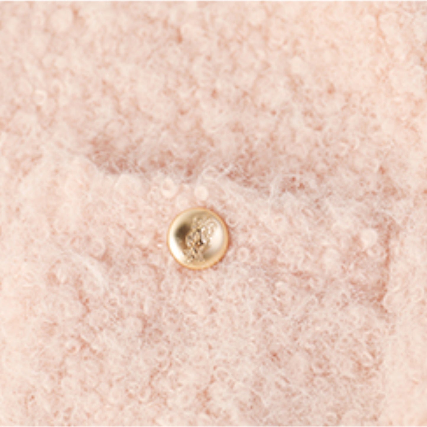 ツイードジャケットのゴールドボタンとブークレ生地のテクスチャを写した拡大写真。