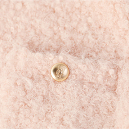 ツイードジャケットのゴールドボタンとブークレ生地のテクスチャを写した拡大写真。