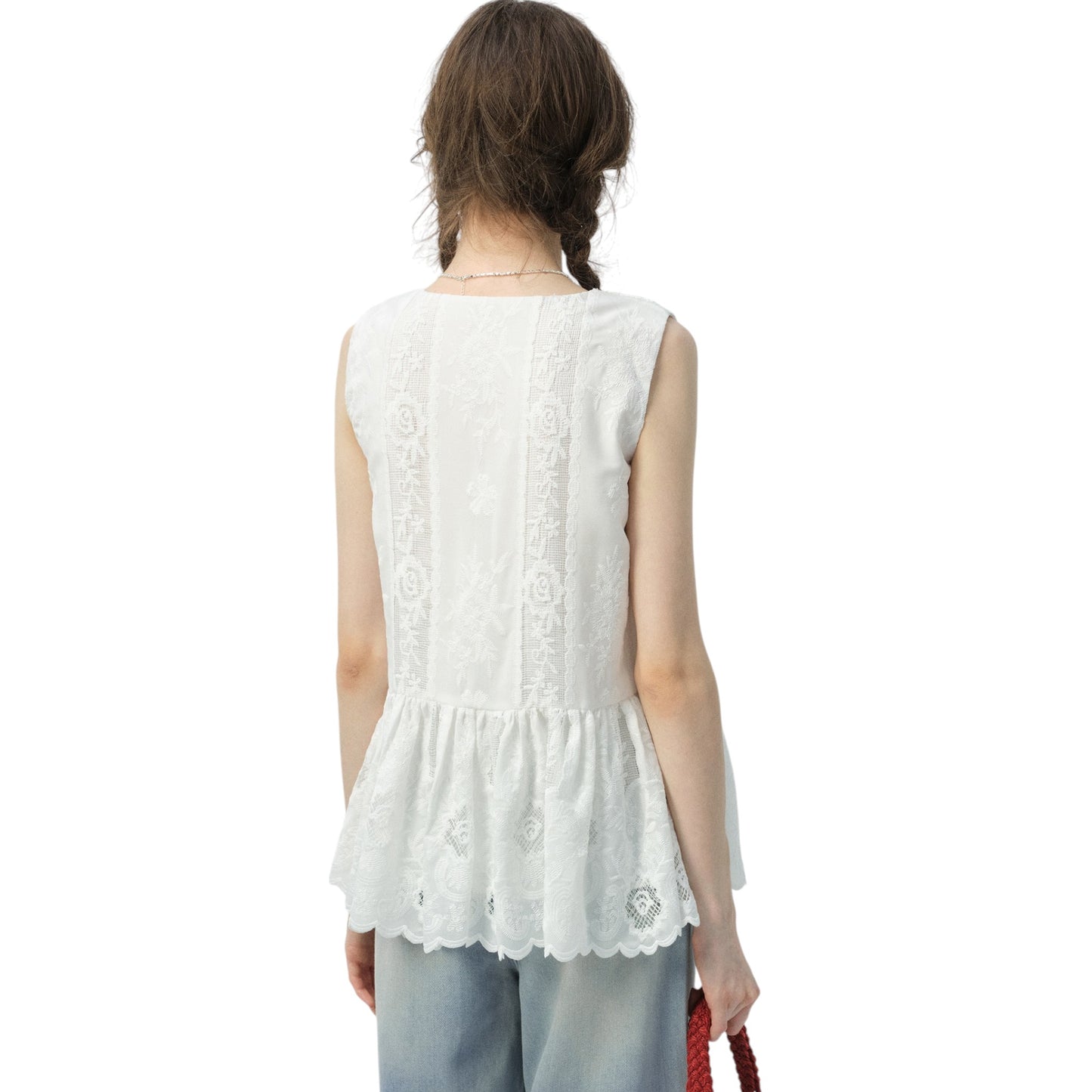 白のペプラムブラウスを着用した女性のサイドビュー。ウエストがシェイプされ、裾が広がる美しいシルエットがわかる。